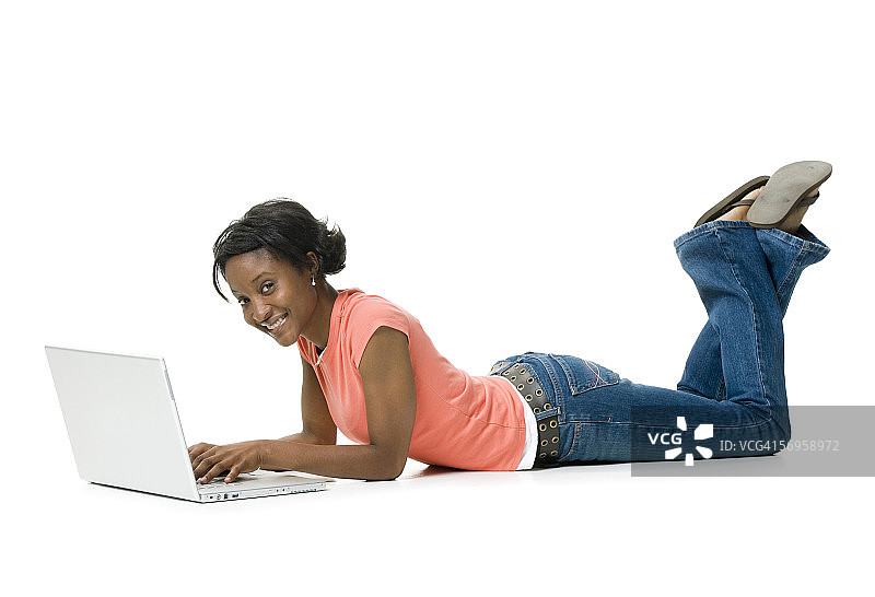 一个年轻女子躺在地板上用笔记本电脑的肖像图片素材