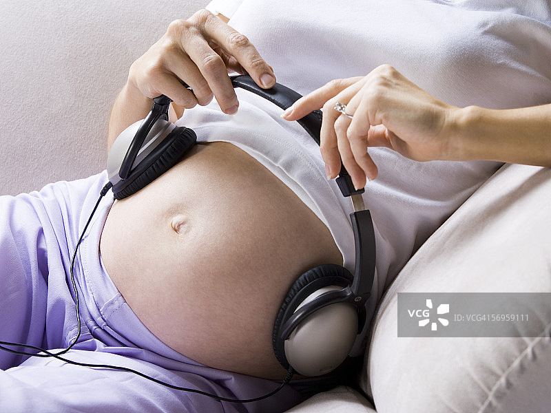 一名孕妇腹部戴着耳机的剖面图图片素材