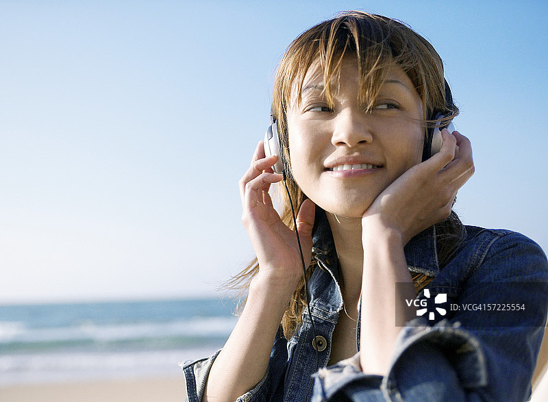 一个在海滩上听音乐的日本女人图片素材