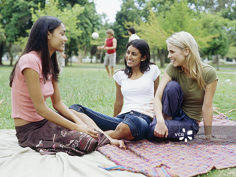 三个年轻女人坐在公园里图片素材