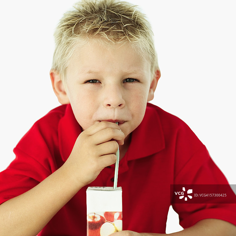一个男孩用吸管喝果汁的特写图片素材