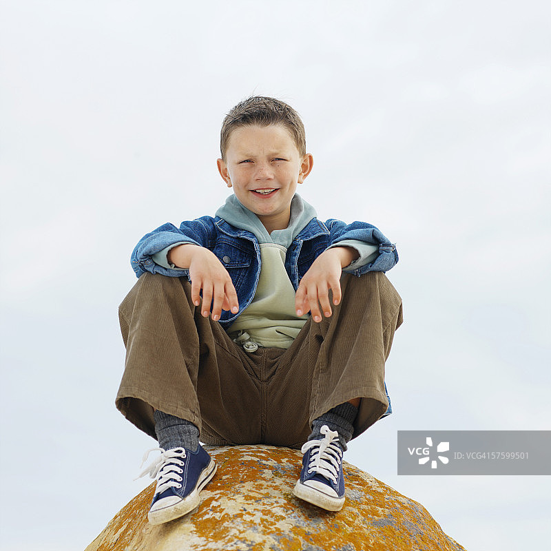 一个男孩坐在岩石上的肖像图片素材