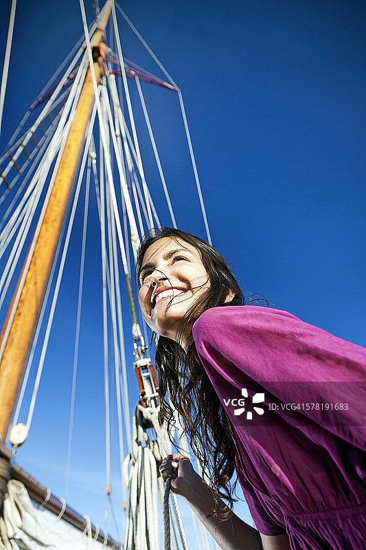 在一艘帆船上微笑的浅黑色的年轻女人图片素材