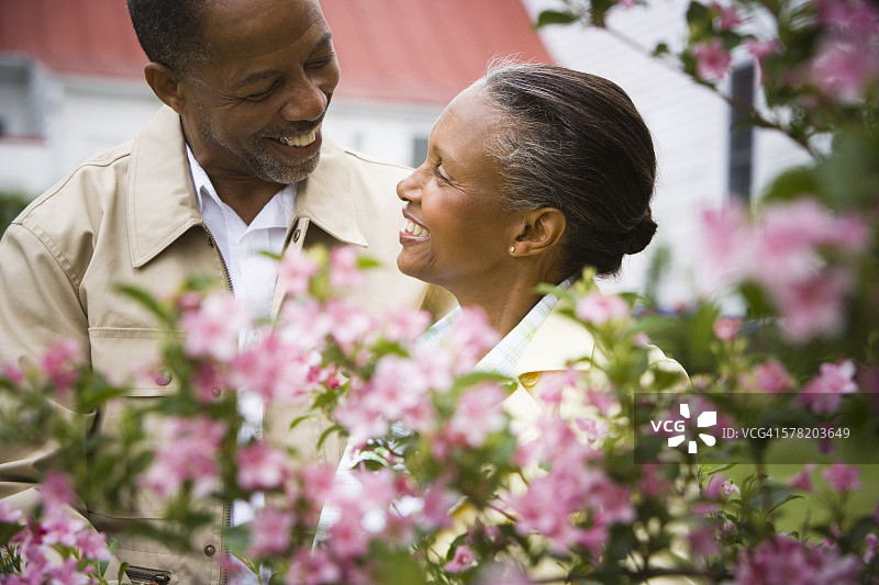 一个高级男子和一个高级女子在鲜花后面微笑的特写图片素材