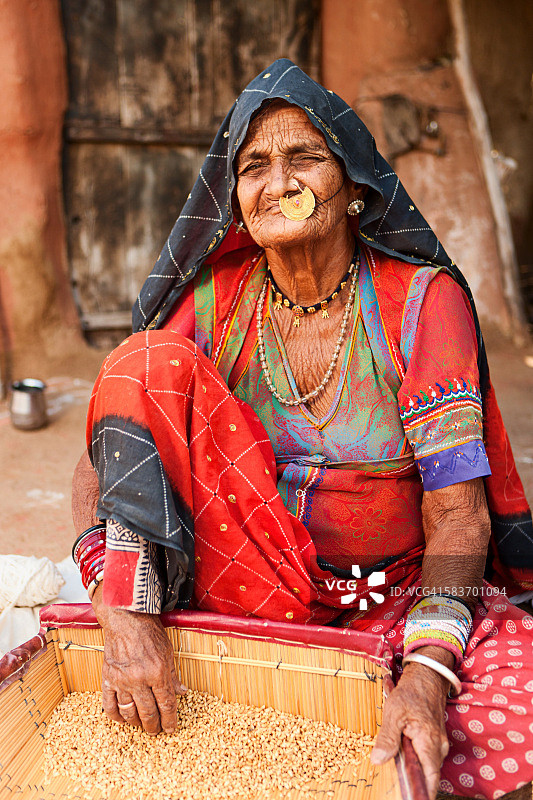 在拉贾斯坦邦的比什诺伊村，一名印度妇女正在筛麦粒。图片素材