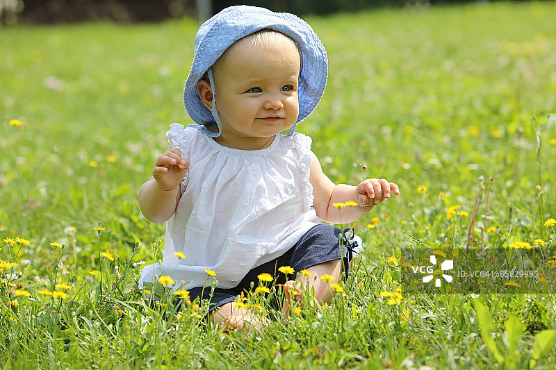 夏天，一个女婴坐在花草地上图片素材