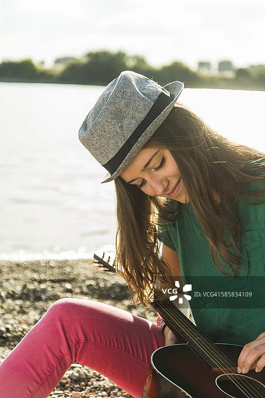 年轻女子在河边弹吉他图片素材