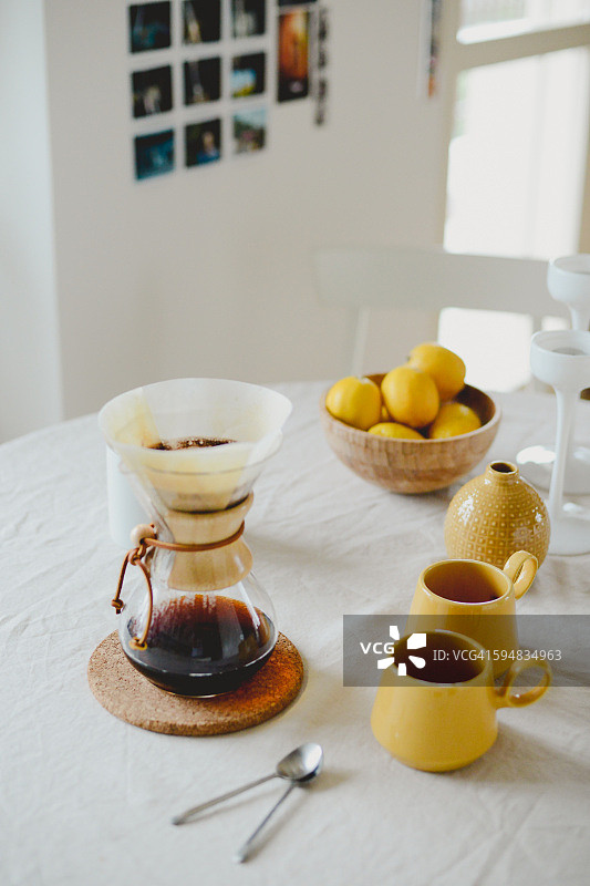 桌子上有咖啡壶、马克杯和水果图片素材