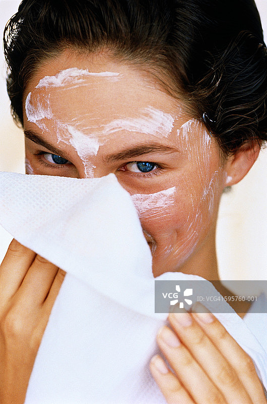 年轻女子用毛巾擦去白色的面霜，特写镜头图片素材