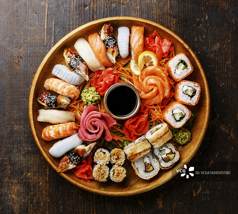 寿司手握寿司，寿司卷和生鱼片装在木制的圆形托盘中图片素材