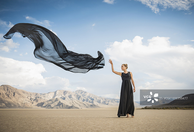 一个西班牙女人在偏远的沙漠里扔围巾图片素材