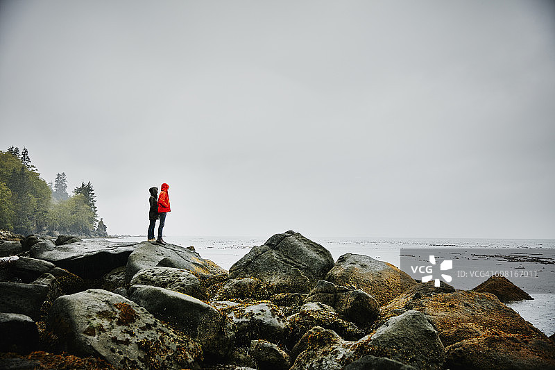 一对夫妇站在海洋海岸线上的巨石上图片素材