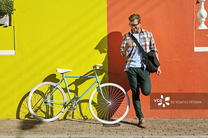 一个年轻人在小巷里骑着自行车和智能手机图片素材