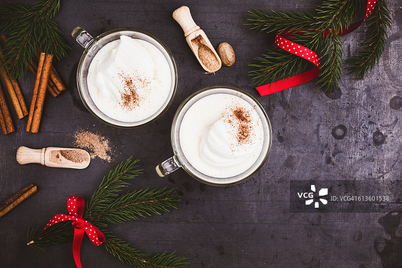 自制蛋酒和掼奶油玻璃杯放在木制的乡村桌子上，圣诞节的款待图片素材