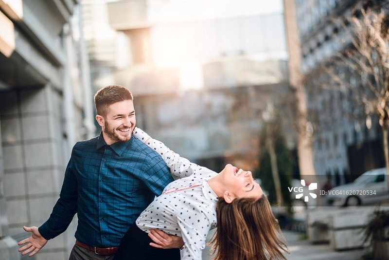 快乐的年轻夫妇在城市街道上跳舞在日落图片素材