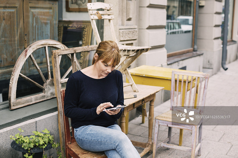 一个女人坐在商店对面的椅子上用手机图片素材