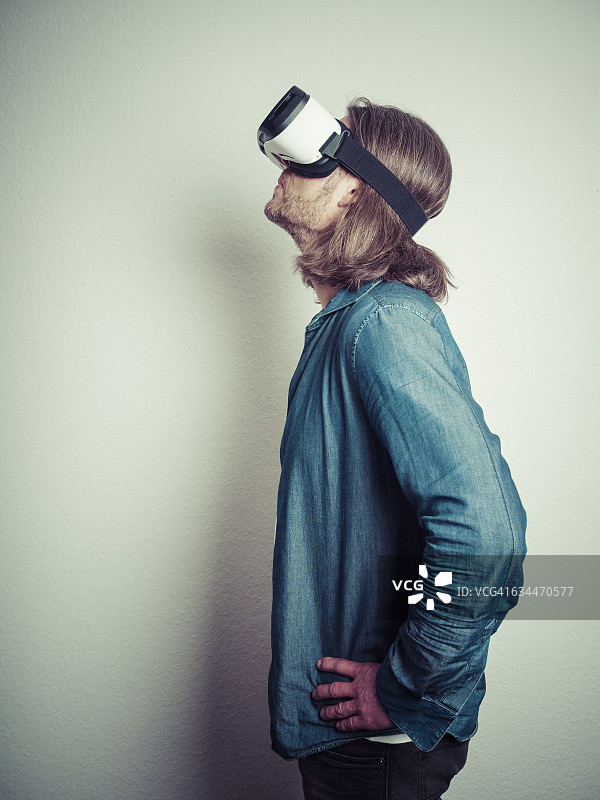 手放在屁股上，戴着虚拟现实眼镜向上看的人图片素材