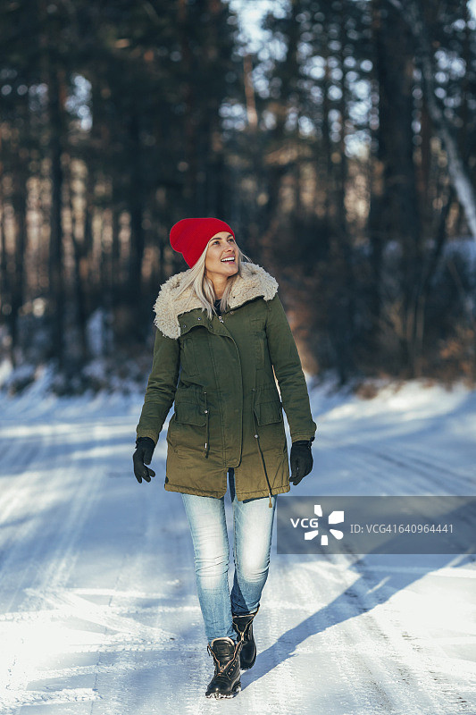 全身快乐的女人走在白雪覆盖的田野上图片素材