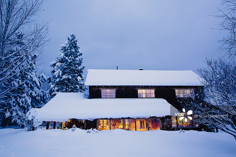 黄昏时雪地里灯火通明的房子图片素材