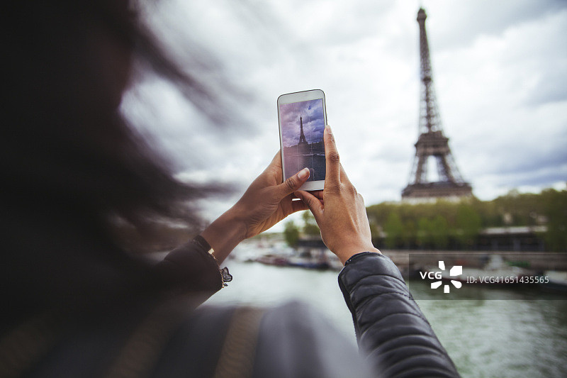 法国，巴黎，一名年轻女子用智能手机给埃菲尔铁塔拍照图片素材
