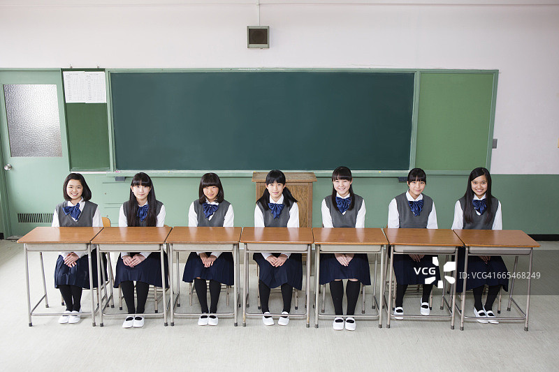 日本女孩并排坐在一排课桌上图片素材