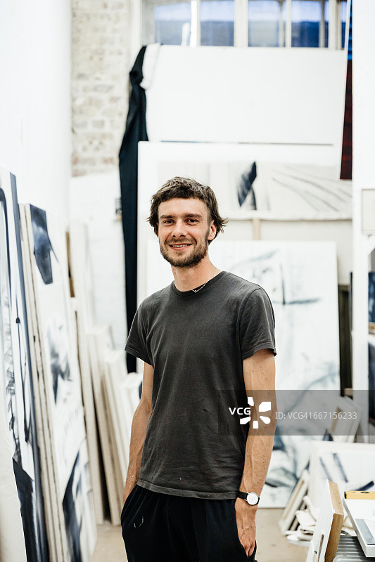 一个年轻艺术家站在工作室里的肖像图片素材