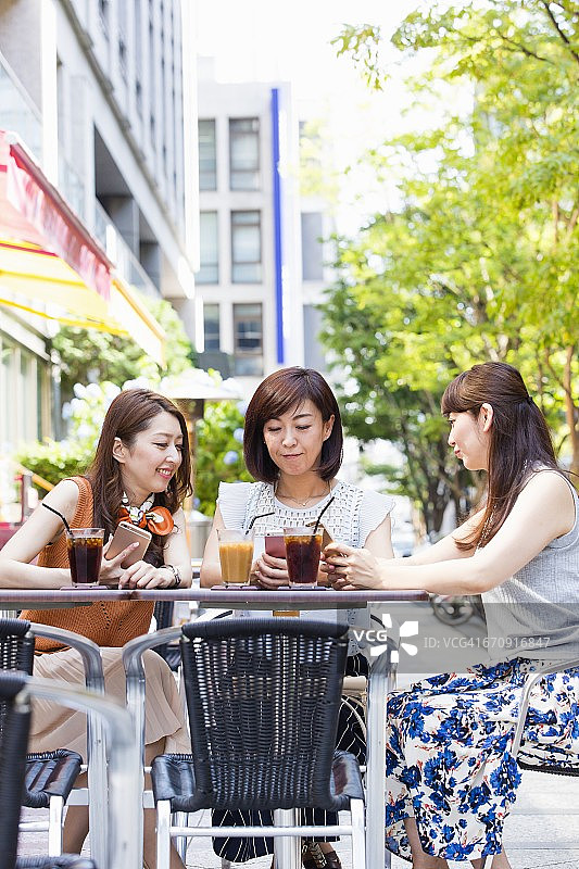商业女性在户外咖啡馆操作智能手机图片素材
