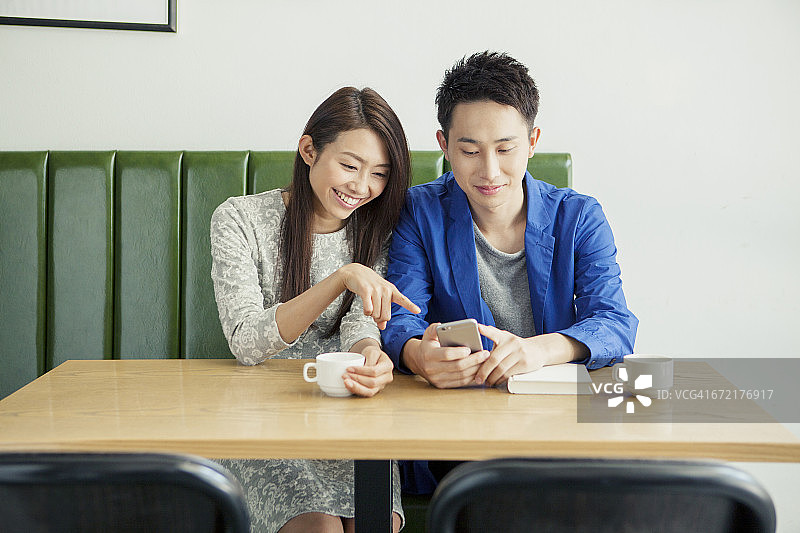 年轻夫妇在咖啡馆看智能手机?图片素材