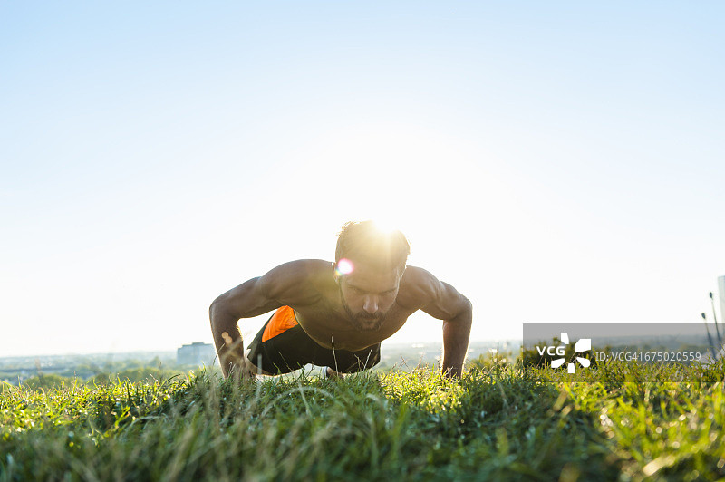在草地上做俯卧撑的男人图片素材