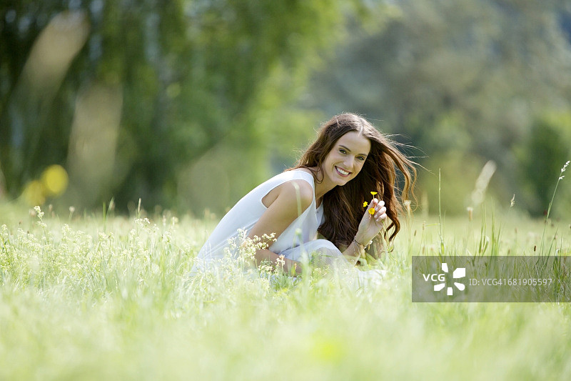 快乐的女人蹲在草地上采花图片素材