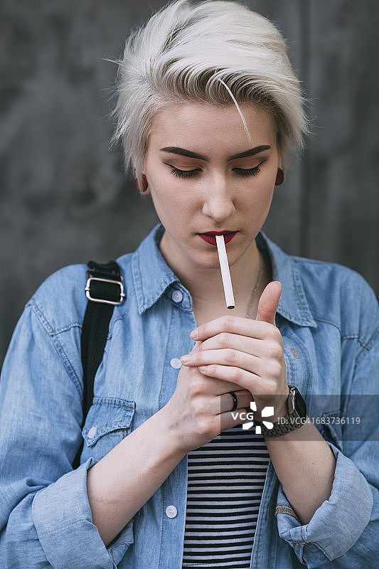 年轻时尚的女子站在户外抽烟图片素材