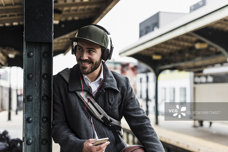 一名年轻人戴着耳机在火车站站台等地铁图片素材