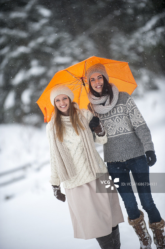 两个朋友在冬天拿着黄伞的肖像图片素材