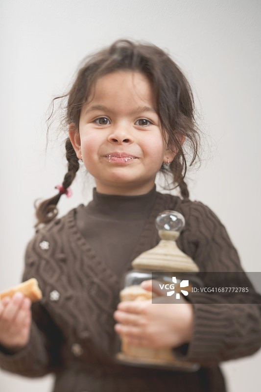 小女孩拿着一个装满油酥饼的储物罐图片素材