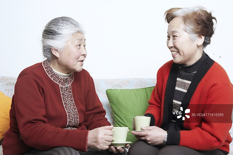 一个年长女人的侧面轮廓坐在沙发上，一个成熟的女人拿着茶杯图片素材
