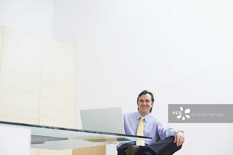 一个商人坐在办公室里，面前放着一台笔记本电脑图片素材