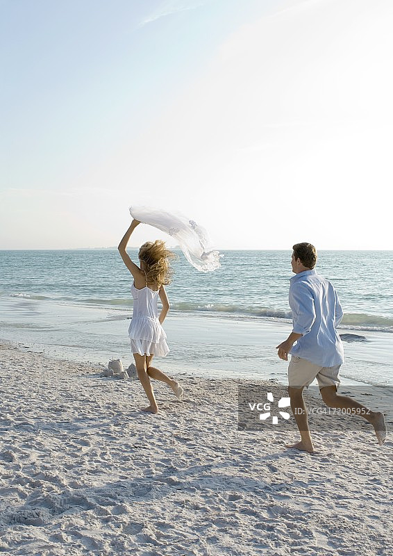 新婚夫妇，男人在沙滩上追女人图片素材