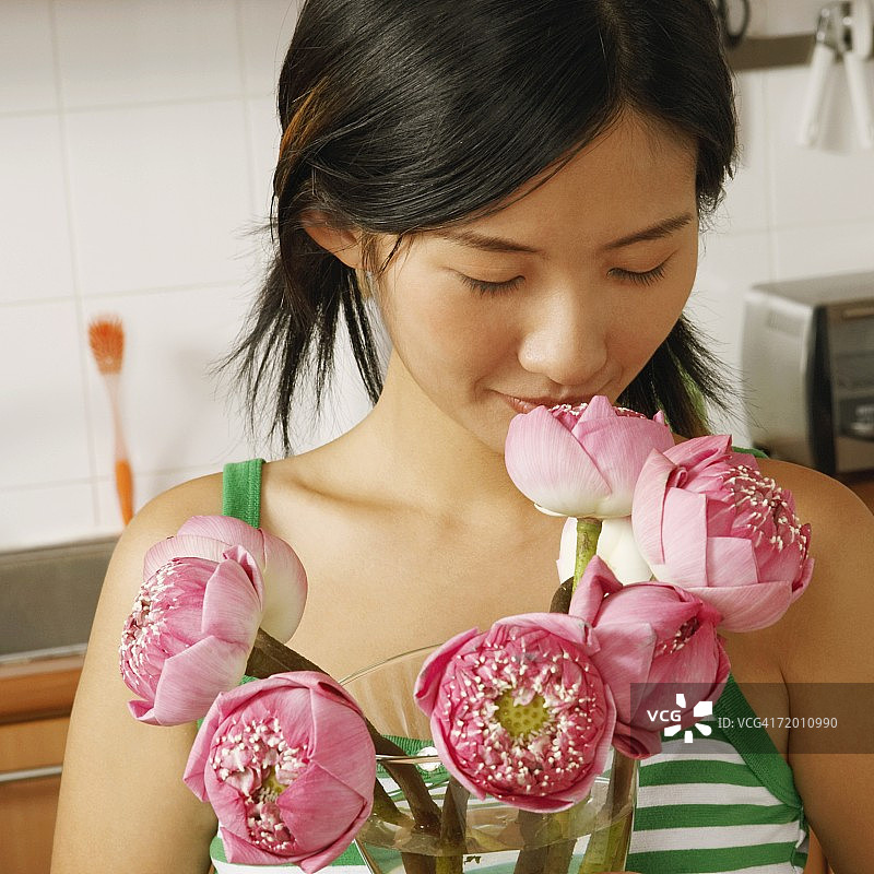 一个年轻女人在厨房里举着花瓶的特写图片素材