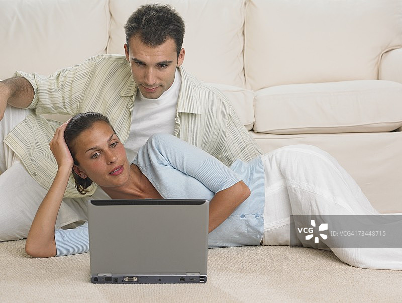 夫妇在地板上使用笔记本电脑图片素材
