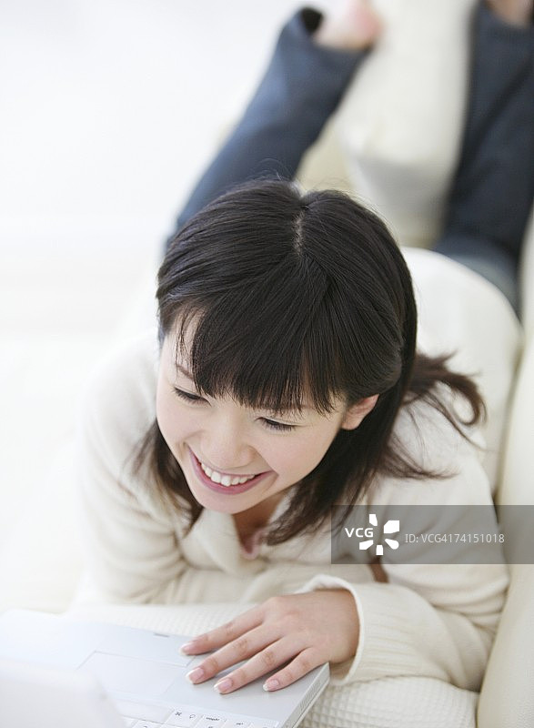 一名日本女子微笑着使用笔记本电脑图片素材
