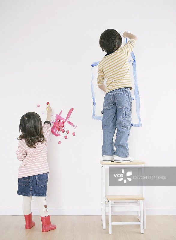 加拿大女孩和男孩在房间的墙上画画图片素材