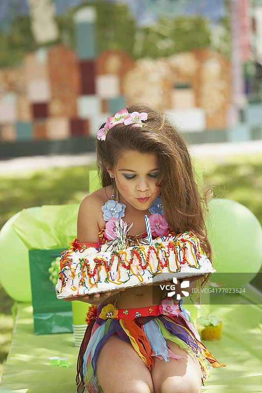 一个女孩吹灭生日蛋糕上的蜡烛的特写图片素材