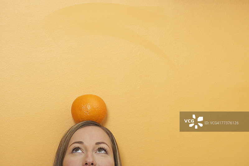 一个橙子躺在一个女人的头上图片素材