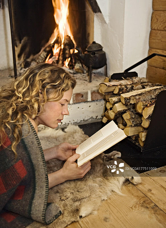 瑞典，一个女人在壁炉前看书。图片素材