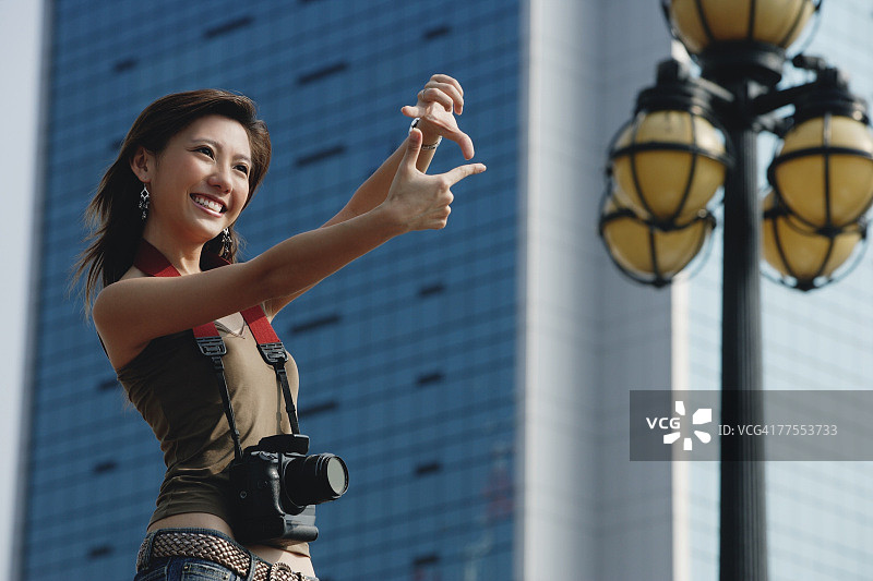 一个拿着相机的女人，用她的手指来构图图片素材