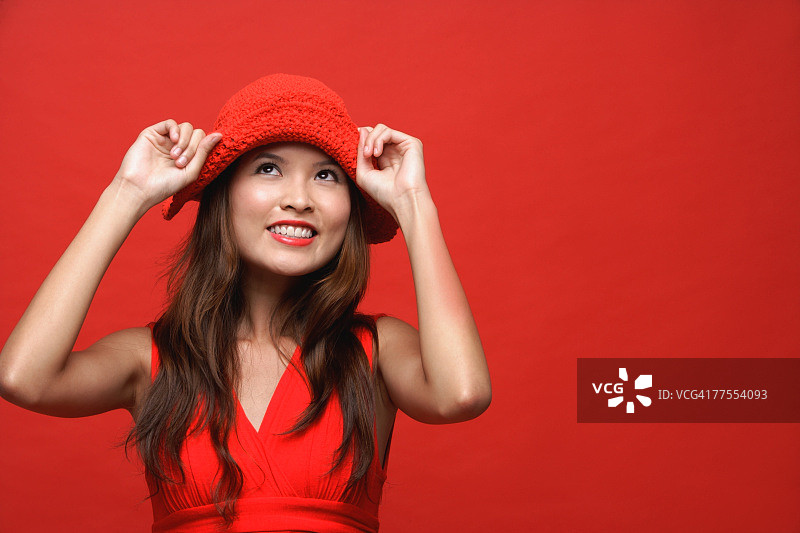 红色背景下，身着红色衣服戴着红色帽子的女人微笑着图片素材