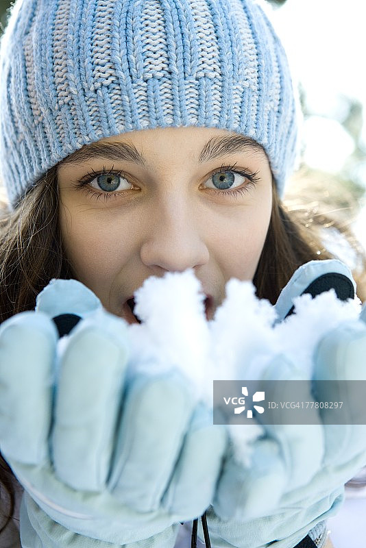 十几岁的女孩吃雪的手，看着相机图片素材