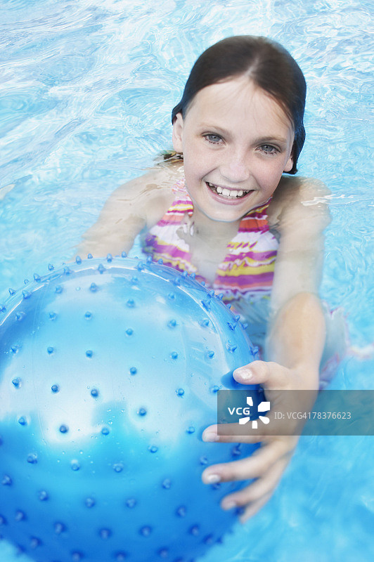 带着球在游泳池里微笑的女孩图片素材