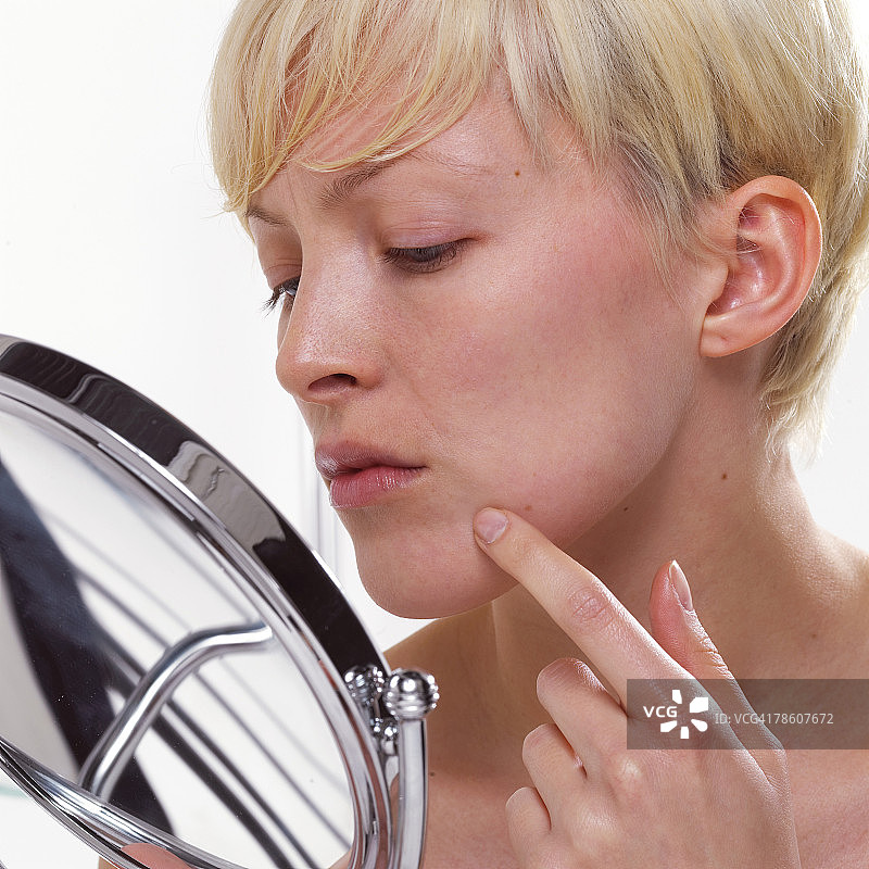 女人在化妆镜前检查粉刺图片素材