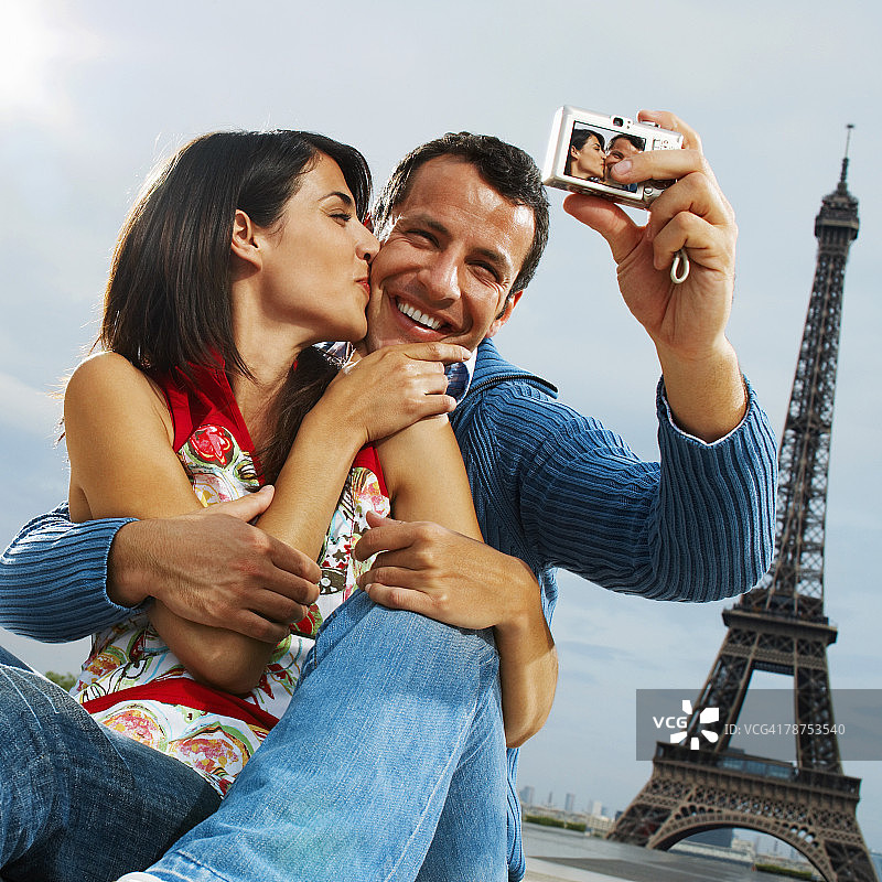 一对情侣在埃菲尔铁塔前用数码相机拍照图片素材